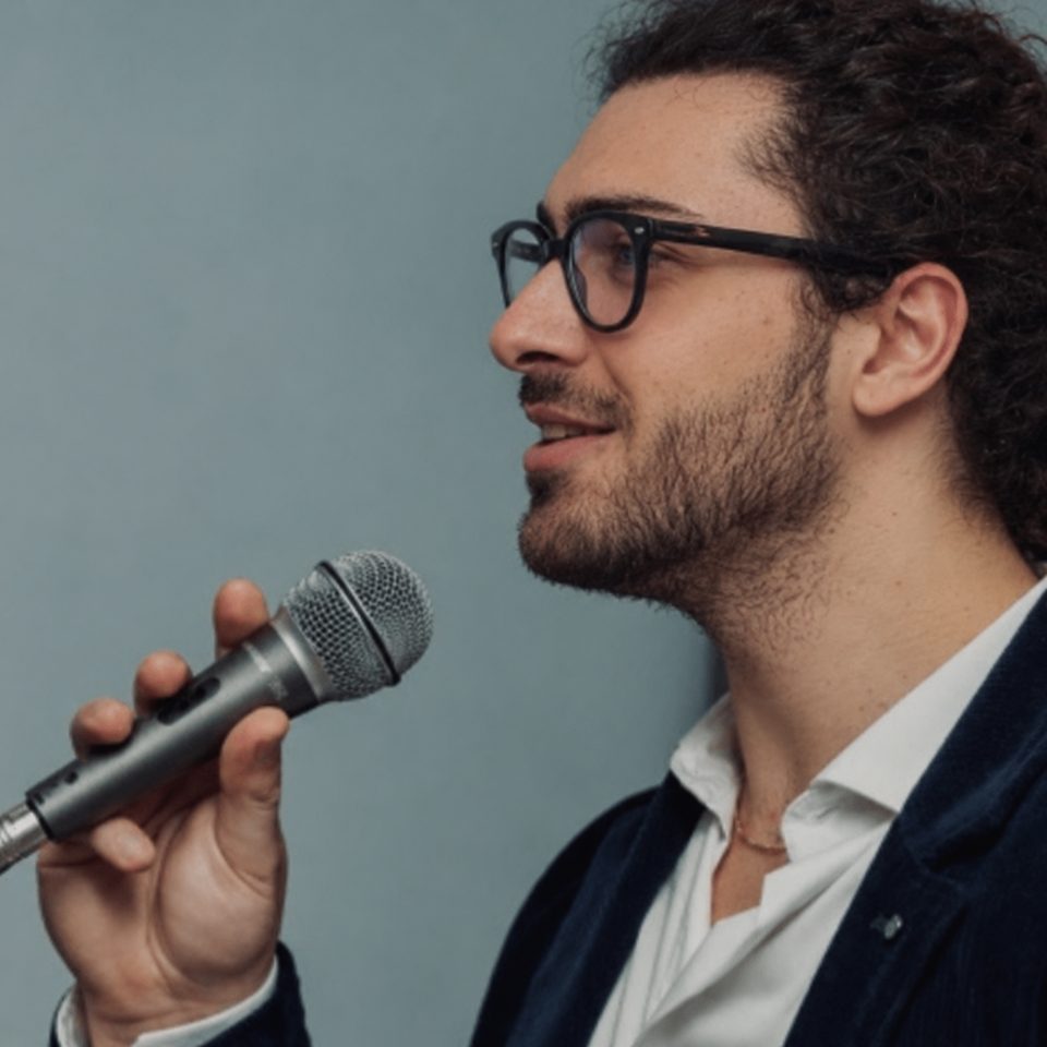 Mattia Ludovico speaking into a microphone at an event